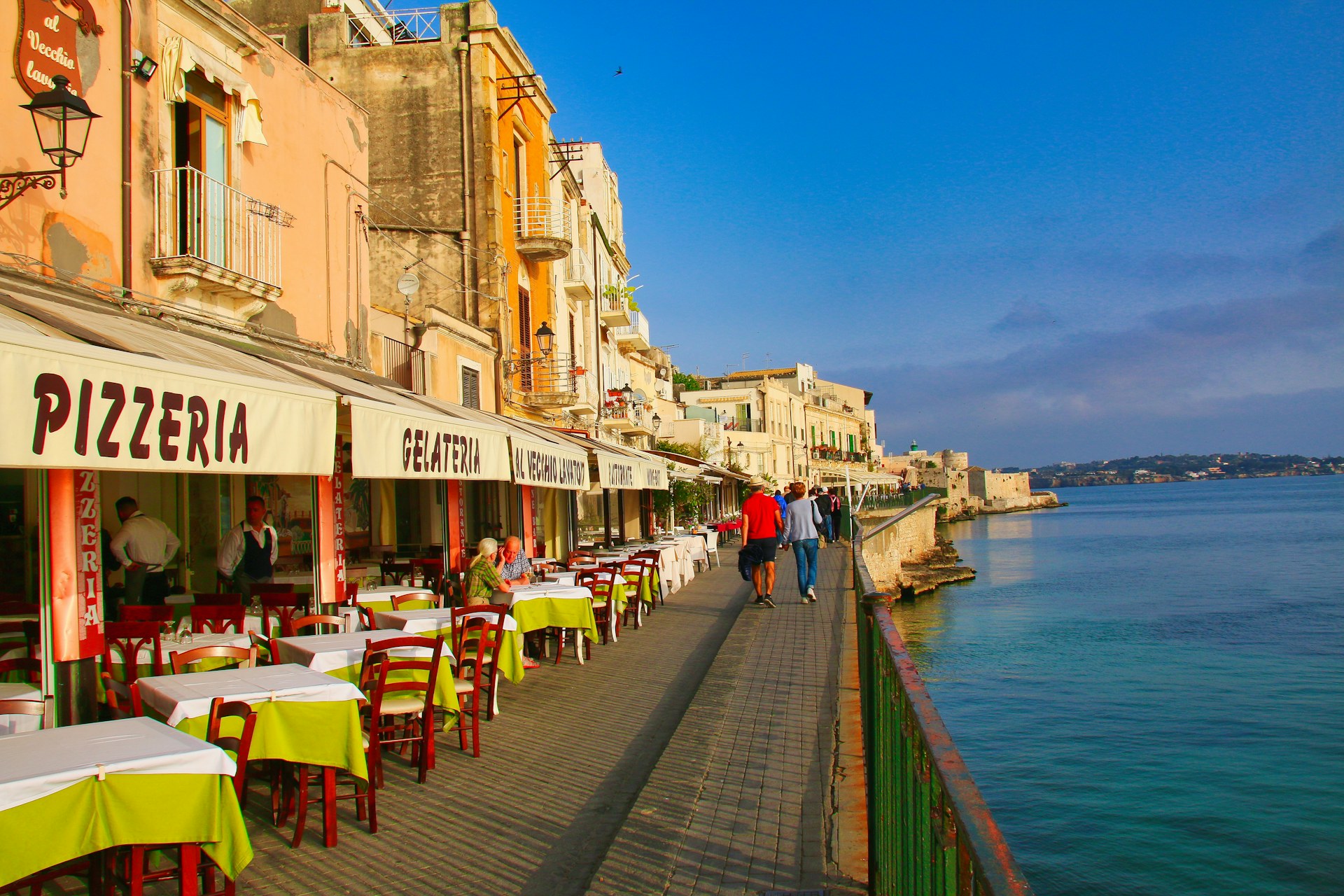 Promenade méditerranéenne avec tables en bord d'eau