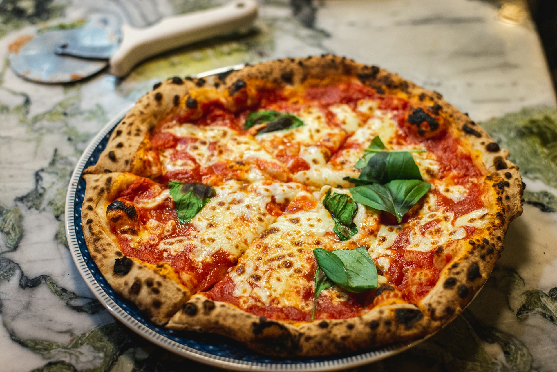 Pinsa Spalato — tomate, cantal, roquette, chorizo, burrata, olives