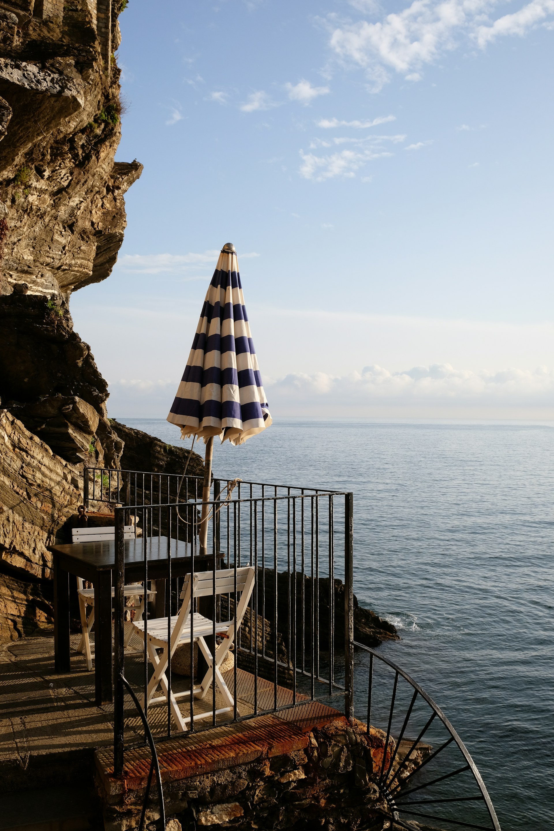 Terrasse méditerranéenne en bord de mer avec parasol rayé